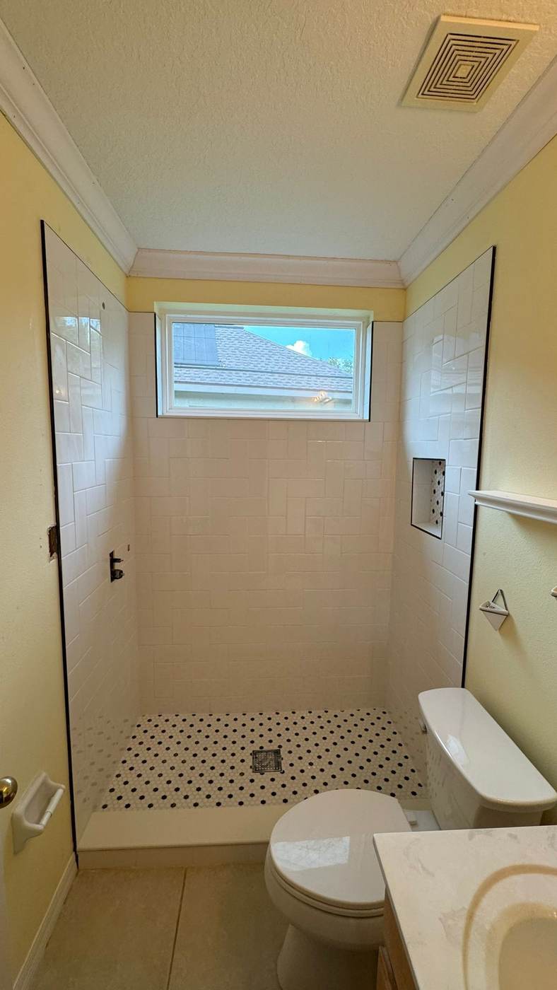 Tiled shower walls with a black and white mosaic floor.