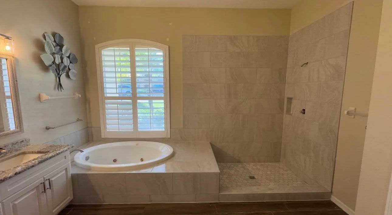 Large neutral tile around a drop-in tub.
