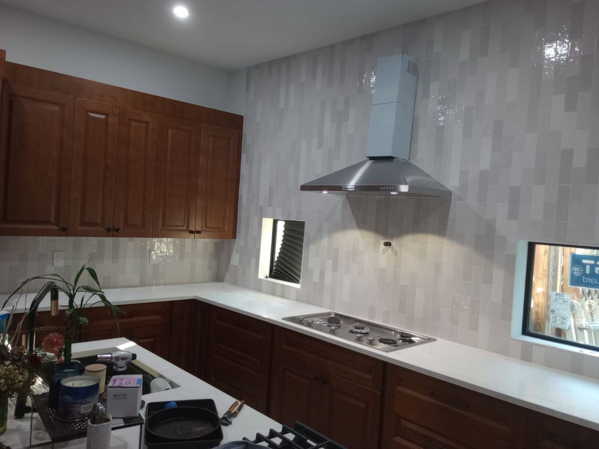 Glazed vertical subway tile backsplash running from the counter up past the range hood